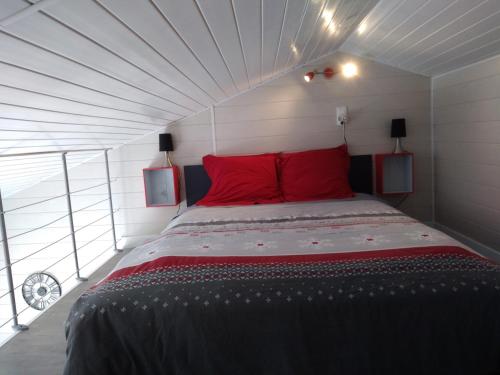 a bedroom with a large bed with red pillows at Un Petit Coin de Vendé in La Flocellière