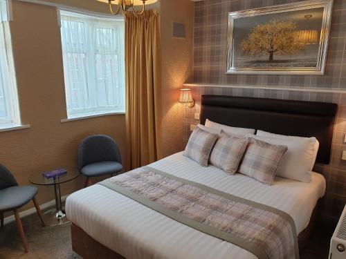 a hotel room with a bed and two chairs at Corona Blackpool in Blackpool