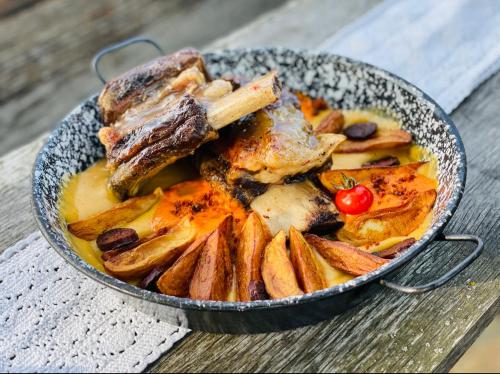 a pan of food with meat and potatoes on a table at István Parkhotel és Gasztrofarm in Sormás