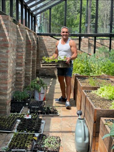a man carrying a tray of plants in a garden at István Parkhotel és Gasztrofarm in Sormás