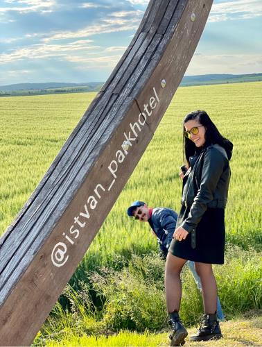 a woman standing in front of a sign in a field at István Parkhotel és Gasztrofarm in Sormás