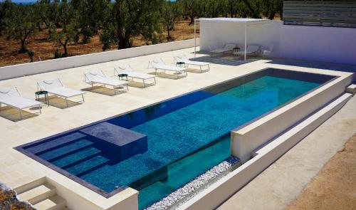 an infinity pool with chairs and a table on a building at Masseria Pezze Galere Piscina privata in Montalbano