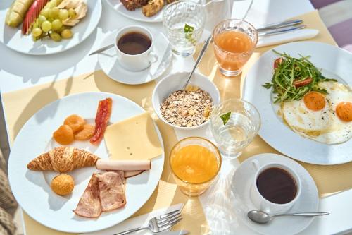 a table with plates of breakfast food on it at Stelia Mare Boutique Hotel in Naousa