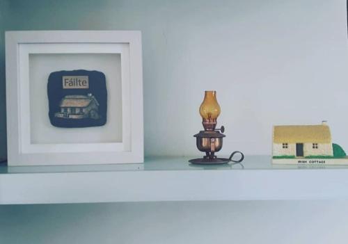 a white shelf with a picture of a house and a lamp at Cozy & Remote Hideaway Gintys Cottage in Ross Port