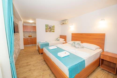 a hotel room with two beds and a kitchen at Guest House S-Lux in Petrovac na Moru