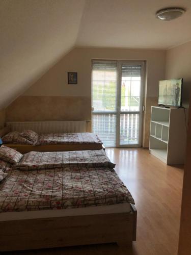 a bedroom with two beds and a sliding glass door at Imre Apartman in Hajdúszoboszló