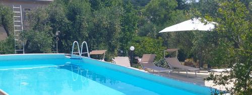a blue swimming pool with chairs and an umbrella at Trullo Le Tre Sorelle in Cisternino