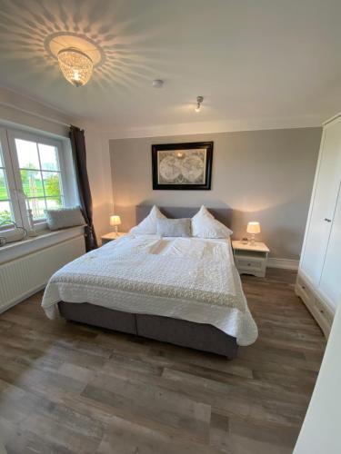 a bedroom with a bed and two windows at Hasselberger Huus in Hasselberg