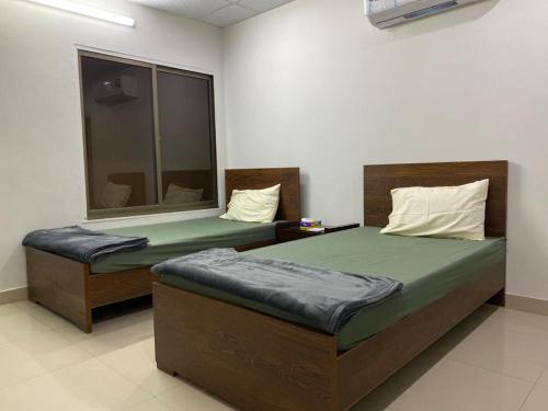 a bedroom with two beds and a window at • Faizi Furnished Apartments in Faisalabad