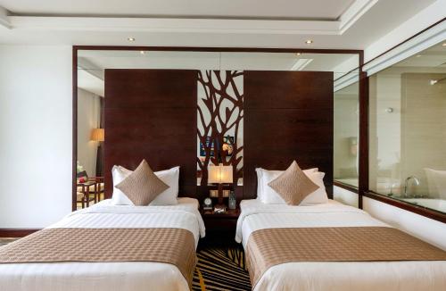 two beds in a hotel room with a mirror at Brilliant Hotel - Afternoon Tea Inclusive in Da Nang