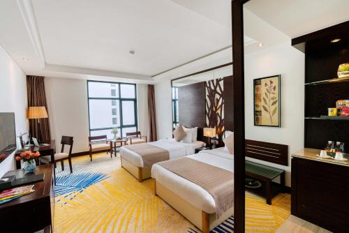a hotel room with two beds and a living room at Brilliant Hotel - Afternoon Tea Inclusive in Da Nang