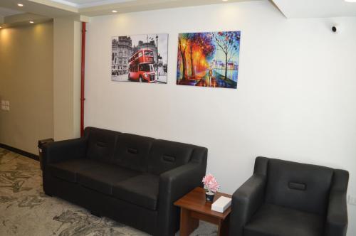 a living room with two black couches and a painting at Royal Inn Residence in Cairo
