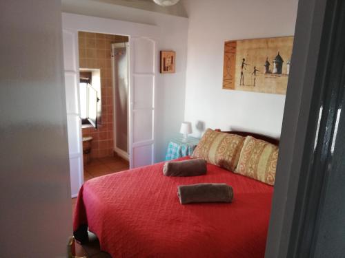 - une chambre avec un lit rouge et 2 oreillers dans l'établissement Casas Manolo, à Vejer de la Frontera