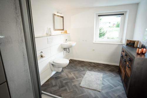 a white bathroom with a toilet and a sink at Landgasthof Bayerwald in Böbrach