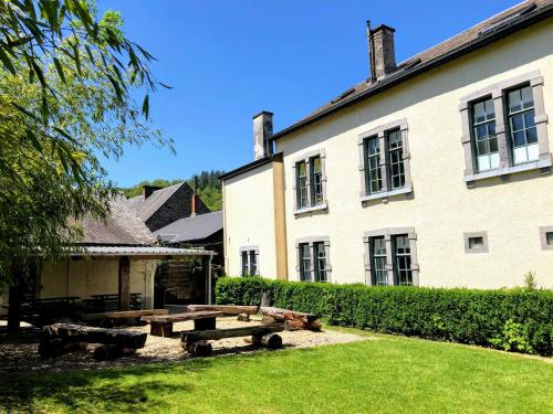 - un bâtiment avec une table de pique-nique devant dans l'établissement Gîte de Groupe de la Semois, à Alle