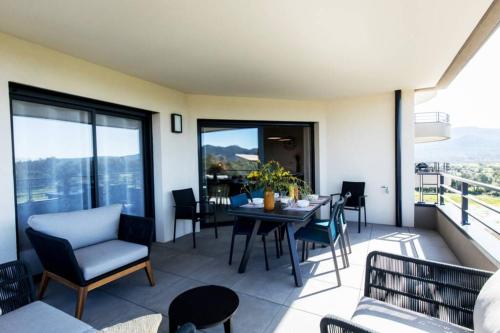 un salon avec une table et des chaises sur un balcon dans l'établissement Les 3 baigneuses : Appartement 2 chambres, neuf proche de toutes commodités, à Porto-Vecchio