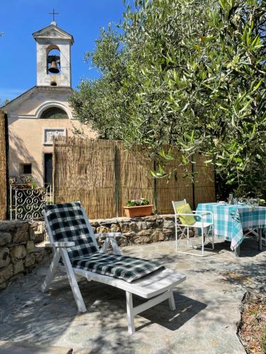 a patio with two chairs and a table in front of a church at Piccola Navetta in Diano San Pietro