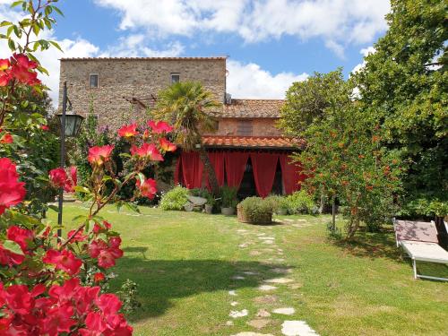 einen Garten mit roten Blumen und einem Gebäude in der Unterkunft Il Pievano B&B in Campiglia Marittima