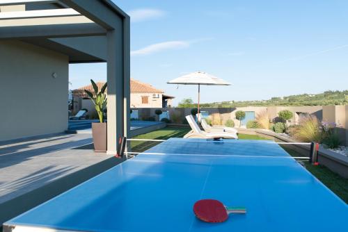 a blue ping pong table on the patio of a house at Minas Sublime Villa, a Magical Sanctuary, By ThinkVilla in Kipseli