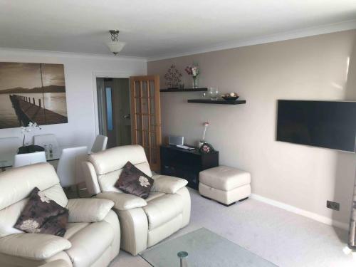 a living room with two white couches and a flat screen tv at Hove Actually with spectacular sea views in Hove