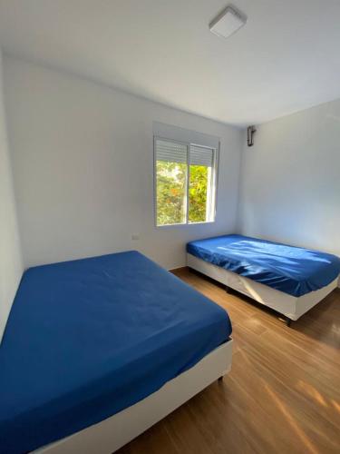 a bedroom with two beds and a window at Apartamento Guarujá Pitangueiras 50 metros da Praia. in Guarujá