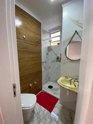a white bathroom with a sink and a toilet at Apartamento Guarujá Pitangueiras 50 metros da Praia. in Guarujá