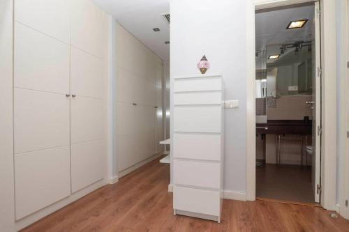 una stanza con armadi bianchi, tavolo e specchio di Apartamento completo - Centro de Algeciras a Algeciras