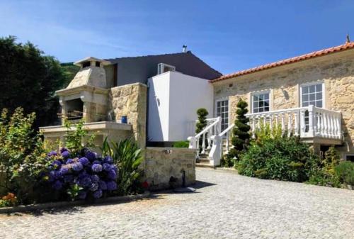 a stone house with a balcony and flowers at Casa Pedro e Inês in Viana do Castelo