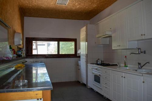 eine Küche mit weißen Schränken, einem Waschbecken und einem Fenster in der Unterkunft Bikers camp in Poreč