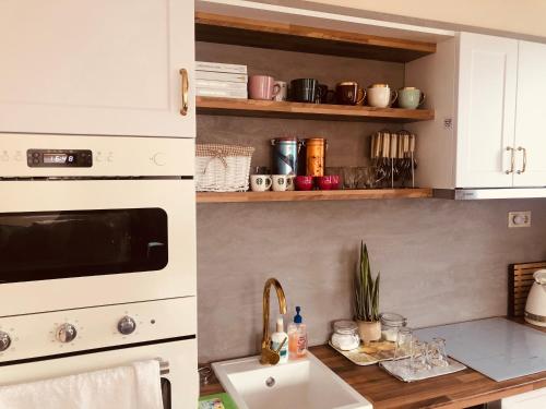 a kitchen with white cabinets and a sink and a counter at Birdland Apartman in Bük