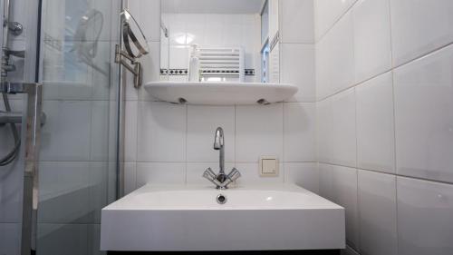 W białej łazience znajduje się umywalka i lustro. w obiekcie B&B Jardin - Schagen w mieście Schagen