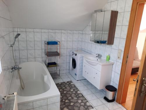a bathroom with a tub and a washing machine and a sink at Ferienwohnung Berger in Gmünd in Kärnten