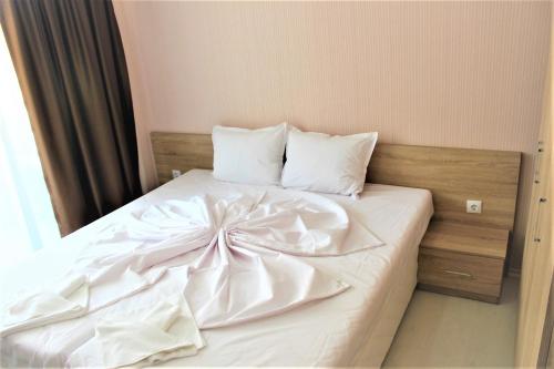 a white bed with a bow on it at Private apartments Stamopolu lux in Primorsko