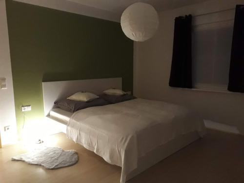 1 dormitorio con cama blanca y pared verde en Apartement am Waldrand, en Bad Wildbad