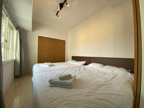 a bedroom with a white bed with two towels on it at Downtown area Spacious cozy room Susukino IK501 in Sapporo