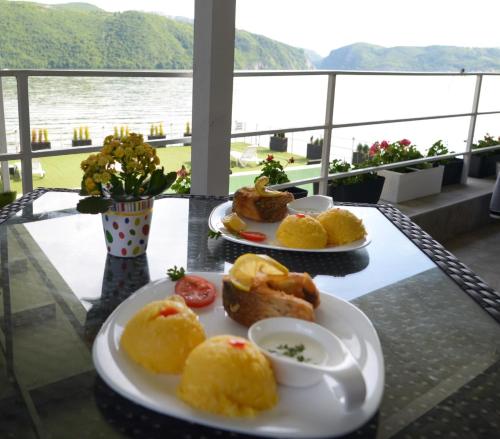 dos platos de comida en una mesa con vistas al agua en Pensiunea Sunshine en Eşelniţa