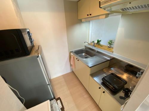 a small kitchen with a sink and a microwave at Downtown area Spacious cozy room Susukino IK501 in Sapporo