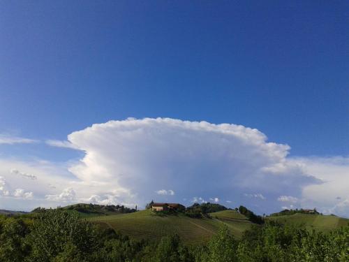a cloud above a green hill with a house on it at B&B Sant'Anna 21 in Monforte dʼAlba