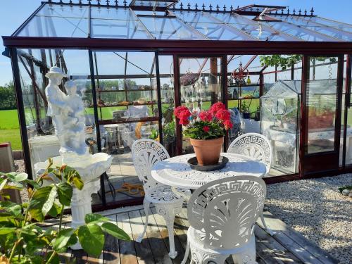 a patio with a table and chairs and a greenhouse at Gårdslägenhet nära Göteborg in Alvhem