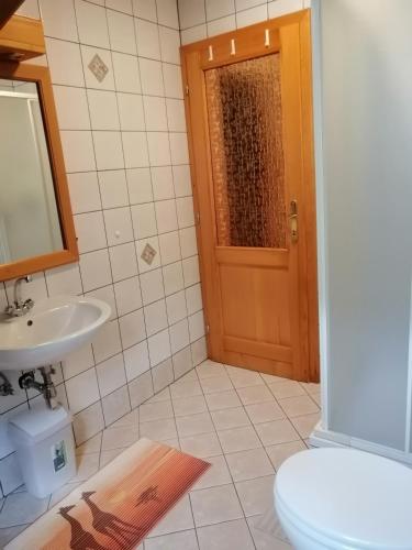 a bathroom with a toilet and a sink and a door at Počitniško stanovanje PLANJA in Soča