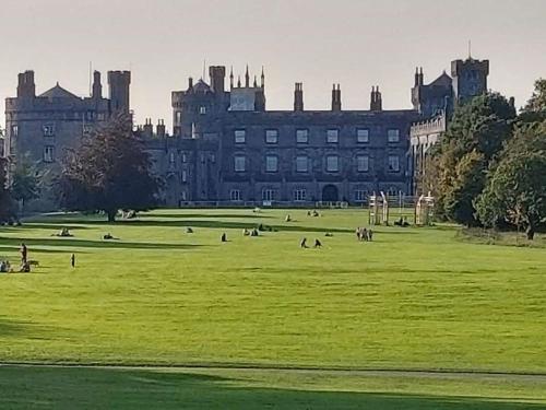 un grand château avec des gens dans un champ en face de celui-ci dans l'établissement Castle Lodge Kilkenny, à Kilkenny