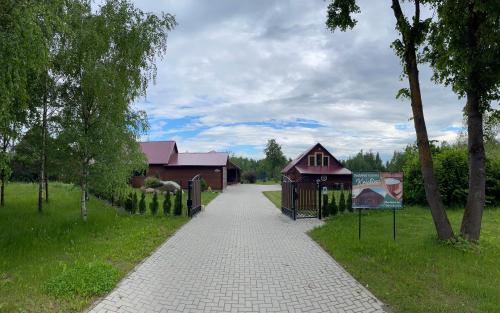 a walkway with a building and a sign in the grass at Sodyba "Kristina" in Biržai