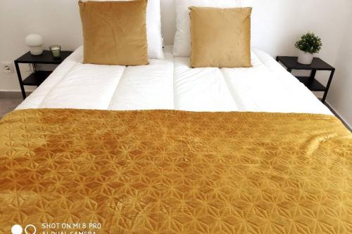 a bed with a yellow and white blanket on it at Old Town House in Loulé
