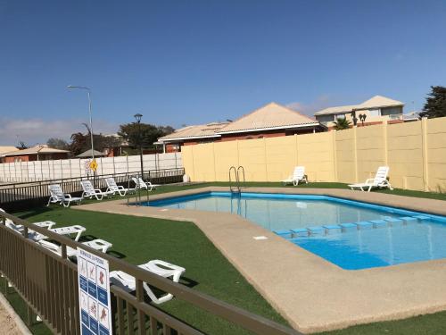 une grande piscine avec des chaises et une clôture dans l'établissement Departamento Portal Caldera, à Caldera