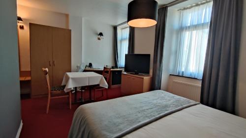 a bedroom with a bed and a desk and a table at La Chrysalide in Étalle