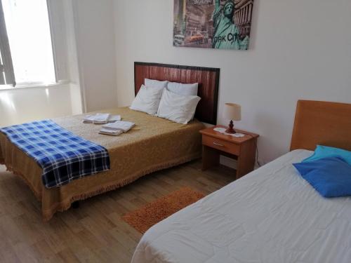 a small bedroom with two beds and a night stand at White Sun Hostel in Lagos