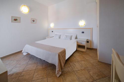 a bedroom with a white bed and a table and lights at Il Gabbiano in La Maddalena