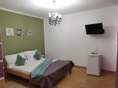 una camera da letto con un letto, una TV e un lampadario a braccio di Vila Happy House a Costinesti