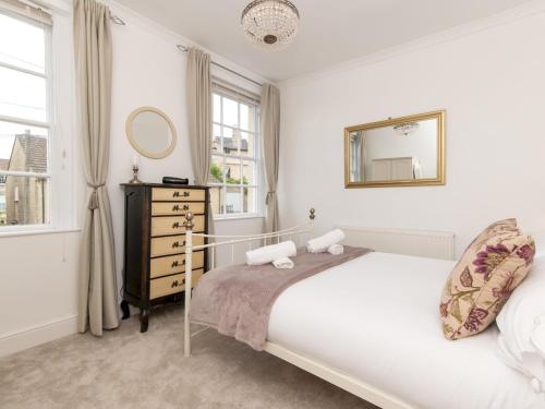 een witte slaapkamer met een bed en een spiegel bij Pass the Keys Stylish 2 Bed central Bath Apartment with Parking in Bath