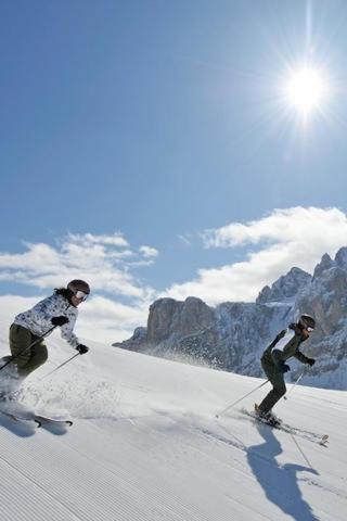 two people are skiing down a snow covered mountain at Parkhotel Post in Chiusa